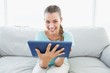 Cheerful woman sitting on couch using tablet pc Cheerful woman sitting on couch using tablet pc