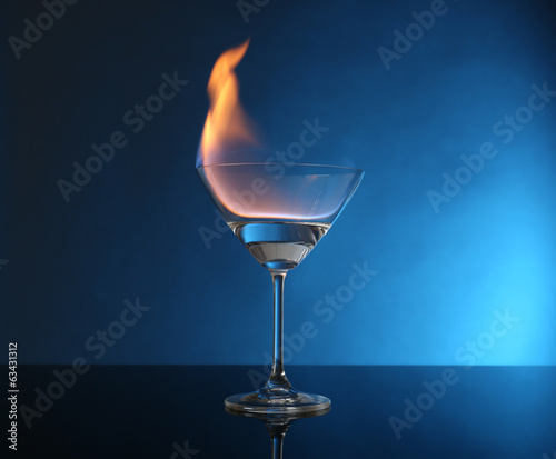 Photo: Glass with burning alcohol on blue background Glass with burning alcohol on blue background