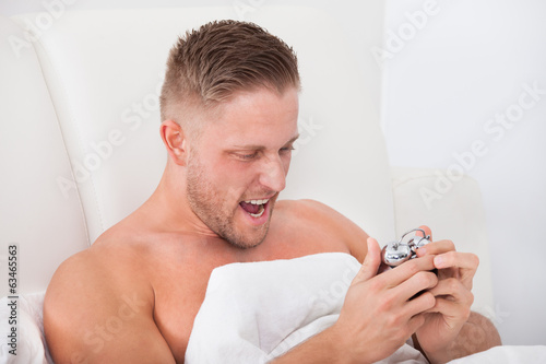 Photo: Man screaming in frustration at his alarm clock Man screaming in frustration at his alarm clock