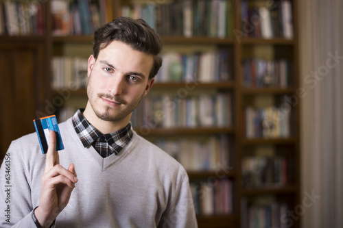 Photo: Attractive young man holding credit card, looking at camera Attractive young man holding credit card, looking at camera