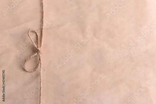 Photo: String tied in bow on beige paper packaging close-up String tied in bow on beige paper packaging close-up