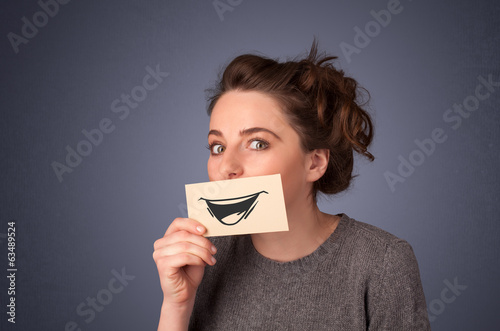 Photo: Happy cute girl holding paper with funny smiley drawing Happy cute girl holding paper with funny smiley drawing