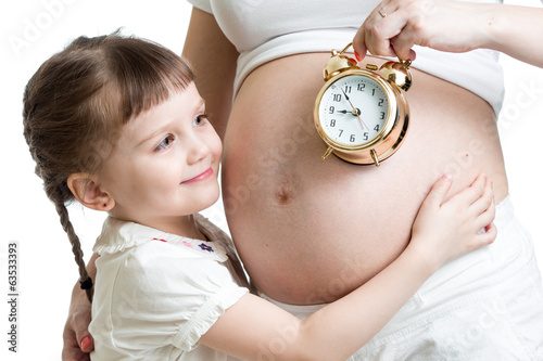Photo: child looking at alarm clock and pregnant woman belly child looking at alarm clock and pregnant woman belly
