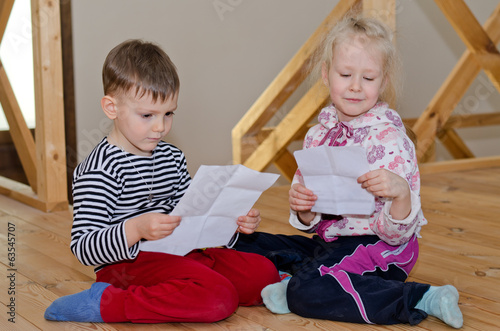 Photo: Little boy and girl sitting together reading Little boy and girl sitting together reading