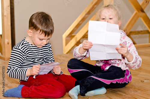 Photo: Little boy and girl sitting together reading Little boy and girl sitting together reading