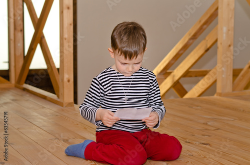 Photo: Little boy kneeling on the floor reading Little boy kneeling on the floor reading