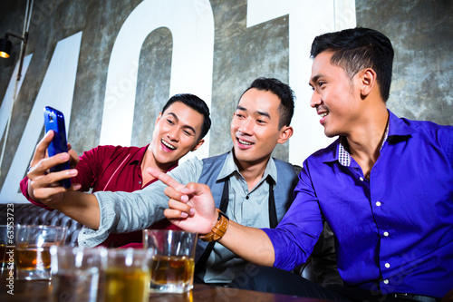 Photo: Asian friends taking pictures or selfies in fancy night club Asian friends taking pictures or selfies in fancy night club