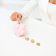 female hand putting euro coins into piggy bank female hand putting euro coins into piggy bank