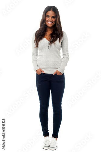 Photo: Smiling young woman posing with hands in pockets Smiling young woman posing with hands in pockets