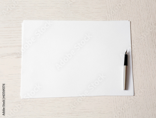 Photo: Blank paper and pen on wooden table Blank paper and pen on wooden table