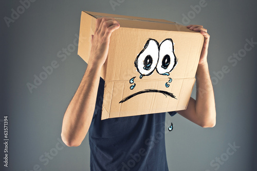 Photo: Man with cardboard box on his head and sad face expression Man with cardboard box on his head and sad face expression