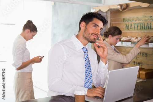 Photo: Businessman using laptop in office cafeteria Businessman using laptop in office cafeteria