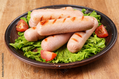 Photo: Grilled sausage on plate on table close-up Grilled sausage on plate on table close-up