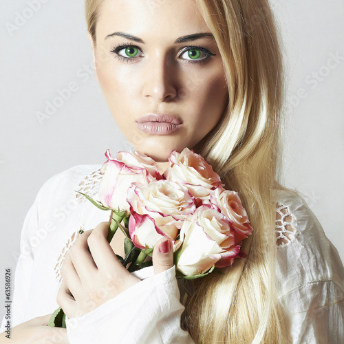 Photo: Beautiful Woman with bouquet of Flowers.Blond girl and roses Beautiful Woman with bouquet of Flowers.Blond girl and roses