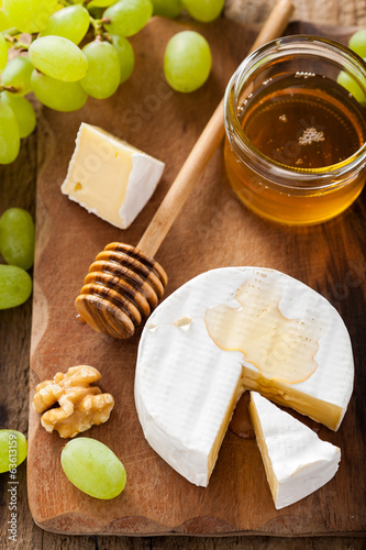 Photo: camembert cheese with grapes, honey and nuts on wooden backgroun camembert cheese with grapes, honey and nuts on wooden backgroun