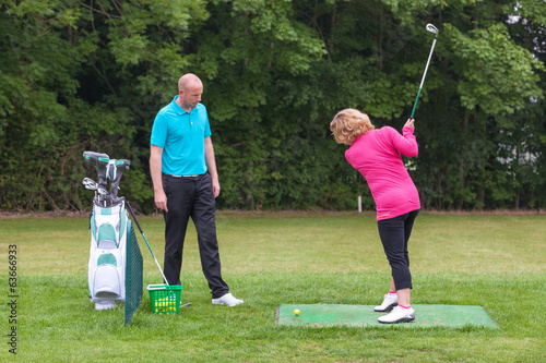 Photo: Golf pro assessing a lady golfers backswing Golf pro assessing a lady golfers backswing