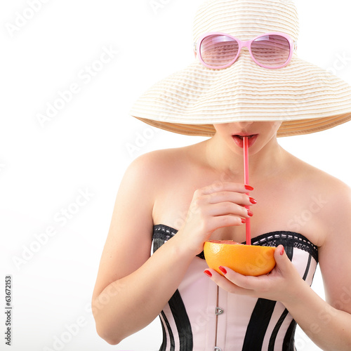 Photo: Beautiful pinup girl drinking juice of grapefruit in sunglssses Beautiful pinup girl drinking juice of grapefruit in sunglssses