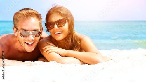 Photo: Happy Couple in Sunglasses Having Fun on the Beach. Summer Happy Couple in Sunglasses Having Fun on the Beach. Summer