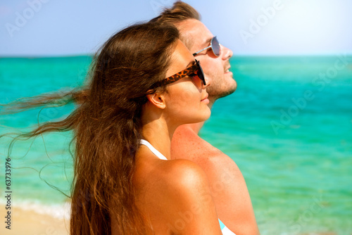 Photo: Happy Couple in Sunglasses Having Fun on the Beach. Summer Happy Couple in Sunglasses Having Fun on the Beach. Summer