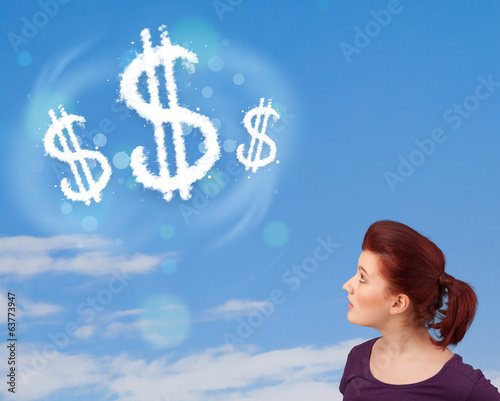 Photo: Young girl pointing at dollar sign clouds on blue sky Young girl pointing at dollar sign clouds on blue sky