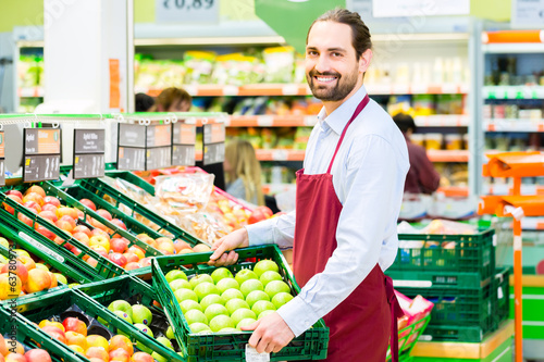 Photo: Supermarkt Angestellter füllt Regale auf Supermarkt Angestellter füllt Regale auf