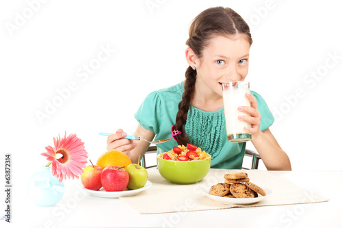 Photo: little beautiful girl have a breakfast on white background little beautiful girl have a breakfast on white background