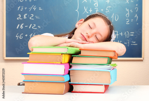 Photo: little schoolgirl sleep in classroom near blackboard little schoolgirl sleep in classroom near blackboard