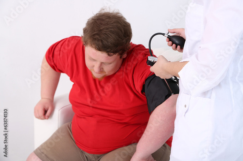 Photo: Doctor examining patient obesity on light background Doctor examining patient obesity on light background