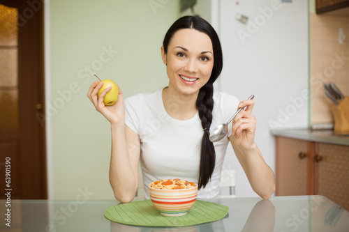 Photo: smiling girl having breakfast with muesli and apple smiling girl having breakfast with muesli and apple
