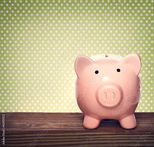 Photo: Piggy bank over green polka dots background Piggy bank over green polka dots background