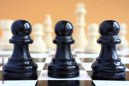 Photo: Chessmen black pawns on background white chess pieces. Chessmen black pawns on background white chess pieces.