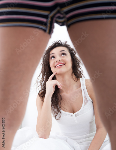 Photo: young woman looking under man leg young woman looking under man leg
