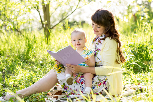 Photo: happy mother reading a book to baby outdoors happy mother reading a book to baby outdoors