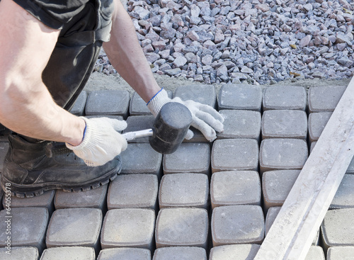 Photo: mason worker making sidewalk pavement with stone blocks mason worker making sidewalk pavement with stone blocks