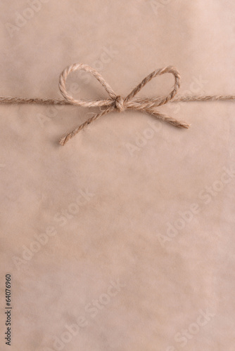 Photo: String tied in bow on beige paper packaging close-up String tied in bow on beige paper packaging close-up