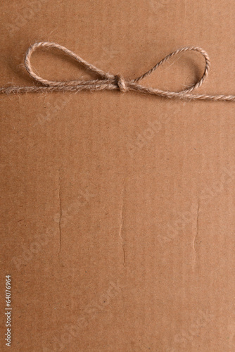 Photo: String tied in bow on brown paper packaging close-up String tied in bow on brown paper packaging close-up