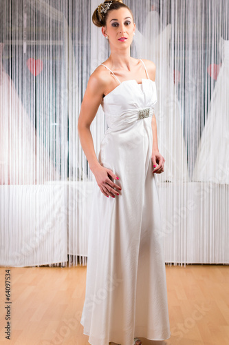 Photo: Frau probiert Brautkleid in Laden an Frau probiert Brautkleid in Laden an