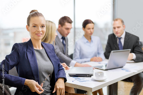Photo: businesswoman with glasses with team on the back businesswoman with glasses with team on the back