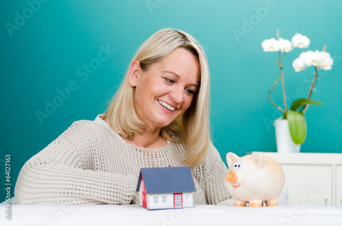 Photo: frau mit sparschwein und miniaturhaus frau mit sparschwein und miniaturhaus