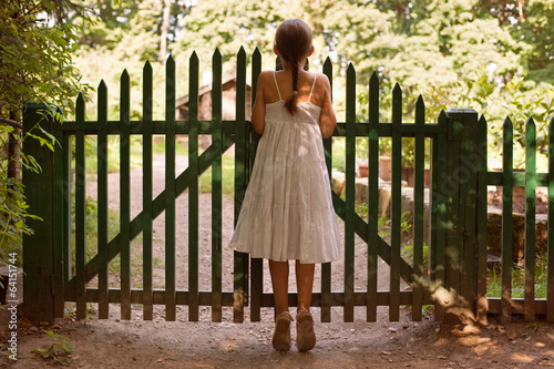 Photo: Girl standing on tiptoes and looking over the fence Girl standing on tiptoes and looking over the fence