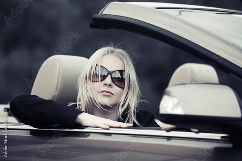 Photo: Young woman driving convertible car Young woman driving convertible car
