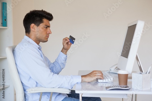 Photo: Casual businessman shopping online at his desk Casual businessman shopping online at his desk