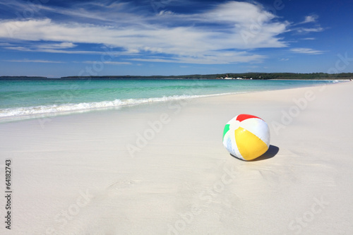 Photo: Colourful beach ball on the seashore by the ocean Colourful beach ball on the seashore by the ocean