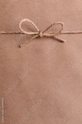 Photo: String tied in bow on brown paper packaging close-up String tied in bow on brown paper packaging close-up