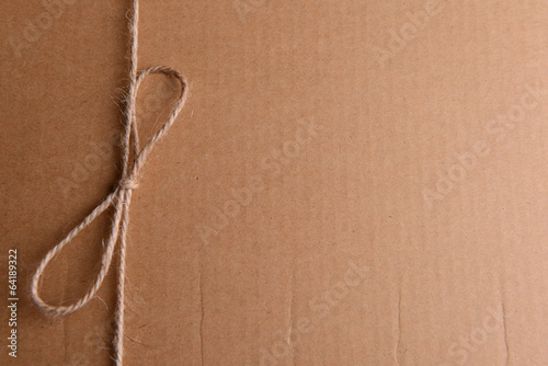 Photo: String tied in bow on brown paper packaging close-up String tied in bow on brown paper packaging close-up