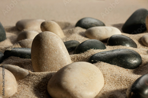 Closeup of stones sticking out of the sand in the sunlight