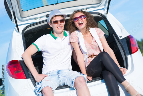 Photo: young couple sitting in the open trunk young couple sitting in the open trunk