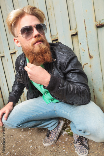 Photo: young man squats and pulls beard young man squats and pulls beard