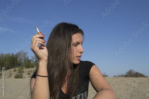 Photo: Young sexy woman with a cigarette in her hand (beach) Young sexy woman with a cigarette in her hand (beach)