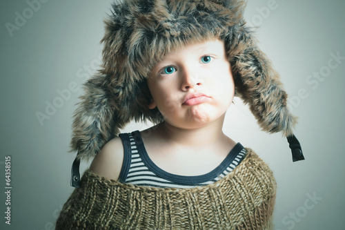 Photo: child in fur Hat.fashion winter style.little funny boy.children child in fur Hat.fashion winter style.little funny boy.children